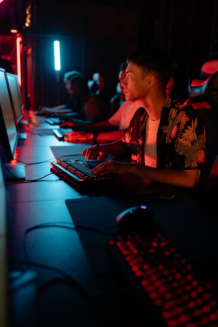 About Gamers in a stylish esports café illuminated by vibrant blue and red neon lights.