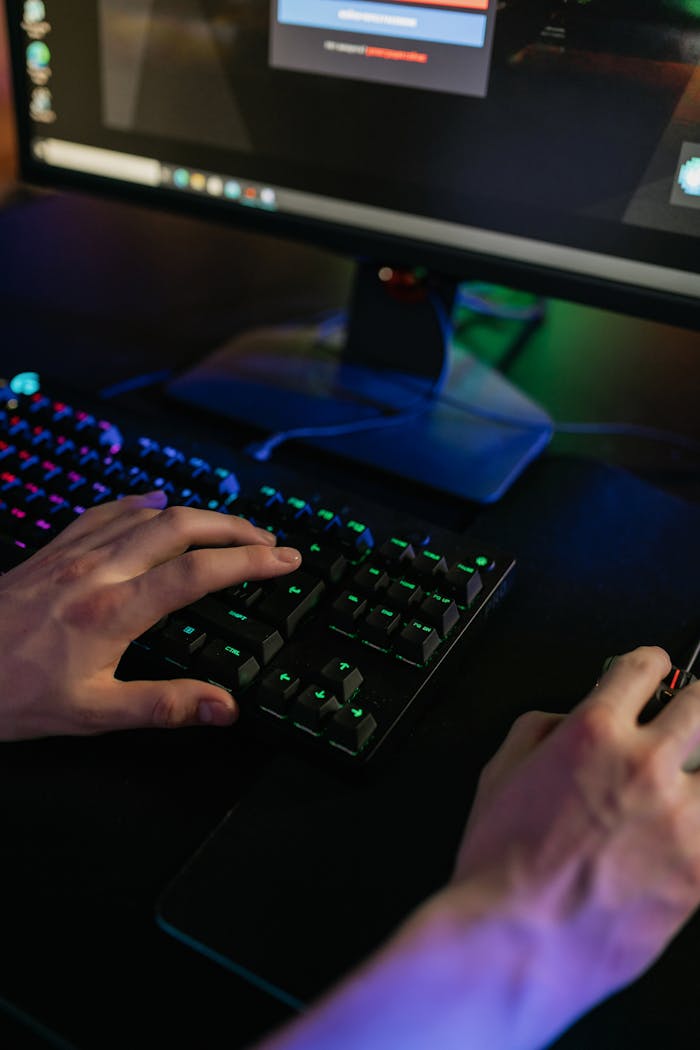 Service Close-up of hands using a keyboard and mouse on a gaming setup with colorful lights.
