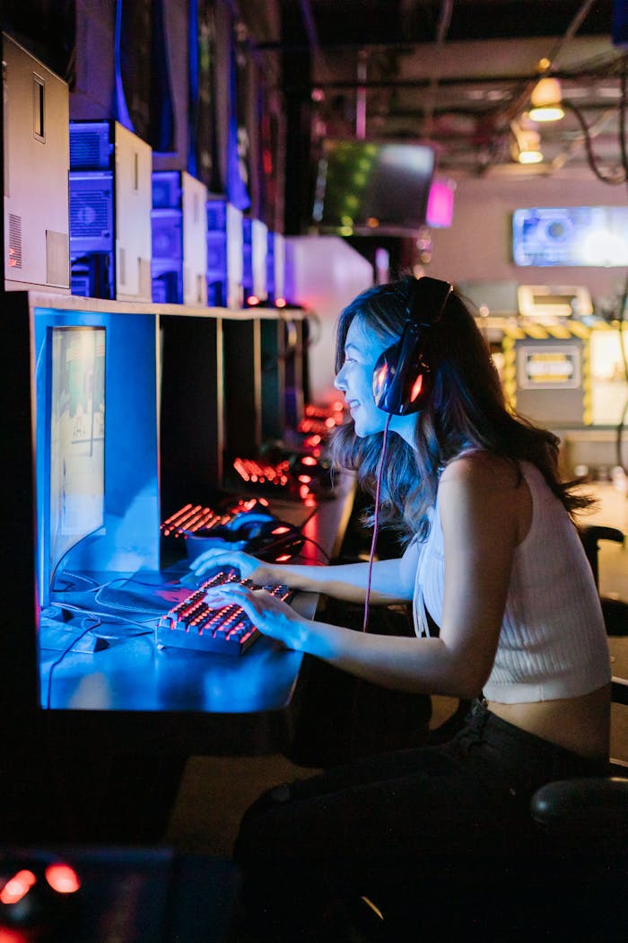 Service A woman intensely focused on a gaming computer in an esports setting with vibrant lighting.